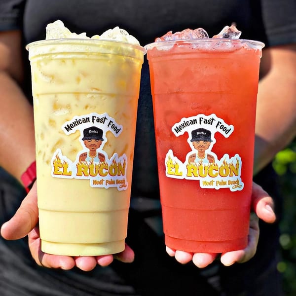 Two hands holding El Rucon Mexican Fast Food drinks, one yellow and one red, with ice.