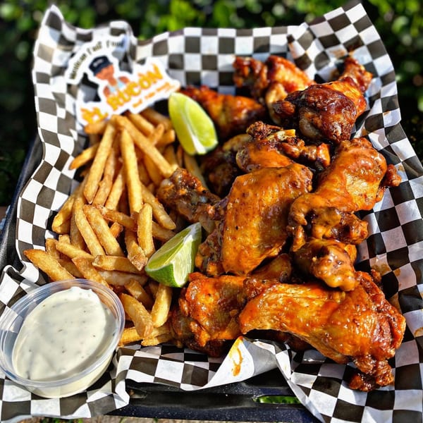 El Rucon's chicken wings and french fries with lime wedges and dipping sauce in a checkered basket.