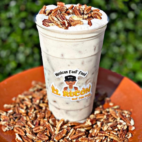 El Rucon's pecan horchata with whipped cream and pecans, surrounded by pecans on an orange plate.